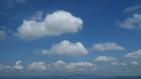 Movement of white clouds against a bright blue sky background during the day Stock Footage 272476912