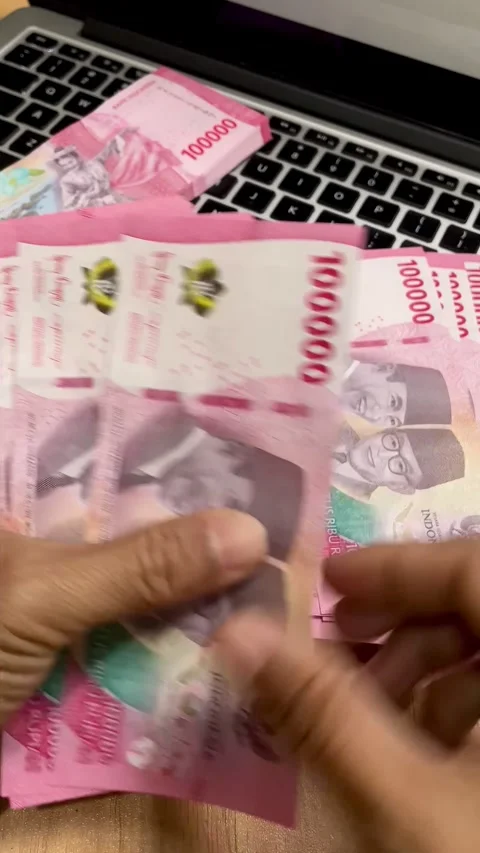 The movement of a woman's hand counting red hundred thousand rupiah banknotes Video stock 295121039