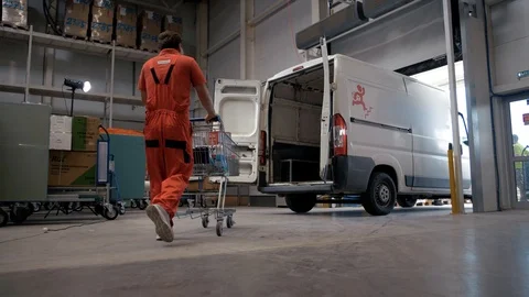 Mover carries a trolley with goods for loading into a transport minibus Stock Footage 102653499