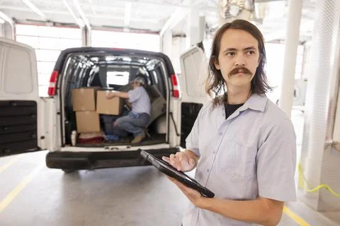 Mover with digital tablet at back of moving van in loading dock Stock Photos