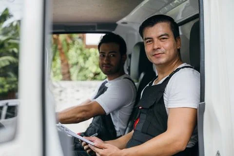 Mover workers an ethnically diverse team driving a truck for relocation service Stock Photos