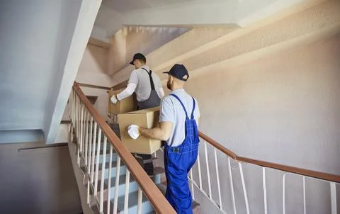 Movers carrying boxes up stairs during residential relocation and delivery Stock Photos