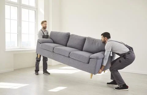 Movers Carrying Sofa Inside Modern Bright Apartment Stock Photos