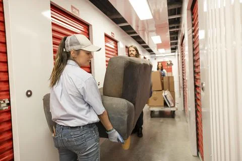 Movers carrying sofa in storage facility corridor Stock Photos