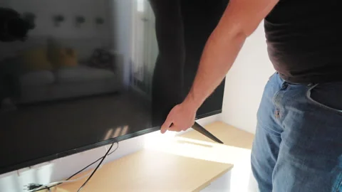 Movers carrying television at home positioning flat screen on wooden stand. Stock Footage 342920226