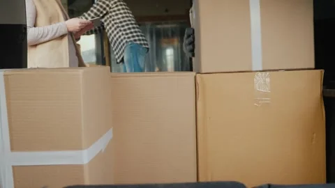 Movers unloading cardboard boxes from truck during residential relocation s.. Video stock 334607665