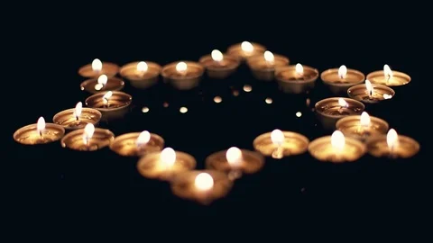 Movie of burning candles in the shape of a star of david on a black background. Stock Footage
