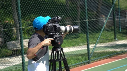 Movie camera. Cameraman changing camera settings focal length, aperture and zoo Stock Footage 111897684
