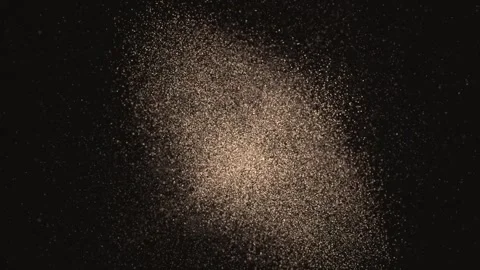 Moving after initial push, golden speck clumps drawing into dense core on black Stock Footage 345726082