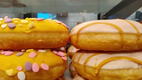 Moving along a bakery shop window with color mixed doughnut Stock Footage 153335564