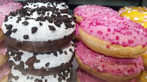 Moving along a bakery shop window with color mixed doughnut Stock Footage 153335582