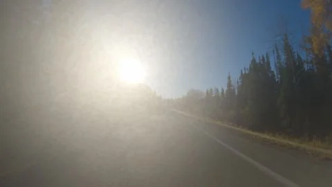 Moving along a paved road looking into the sun with considerable sun flare  Stock Footage 287857459