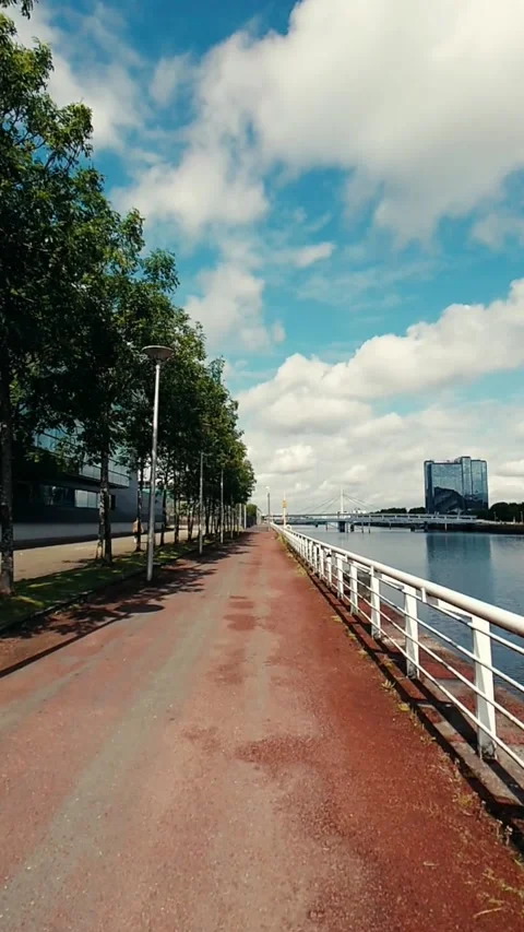 Moving along a red asphalt path next to a river - Vertical Video Video stock 200401101