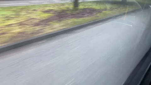 Moving along street grass from inside bus pov real time Stock Footage 302480243
