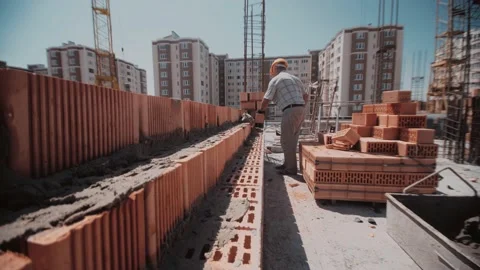 Moving along a wall of red bricks to a builder who builds it 스톡 동영상 143787193