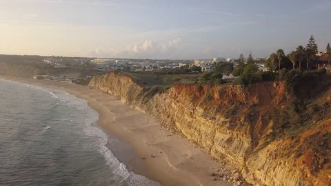 Moving backward and downward drone shot of cliffs by ocean at golden hour Vidéo 98365967