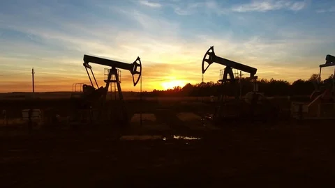 Moving between two working oil pumps to sunset Stock Footage 81319628