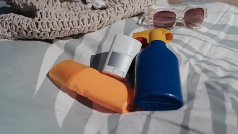 Moving the camera away from sunscreen bottles laid out on a towel Stock Footage 313290613