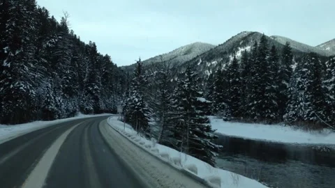 Moving camera down winter highway in mountains along side river Stock Footage 266327801