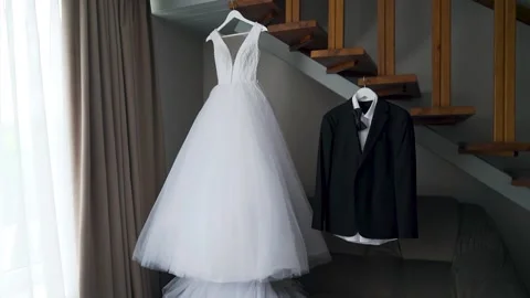 Moving camera. The dress of the bride and groom to hang in a room near stairs Stock Footage 206058258
