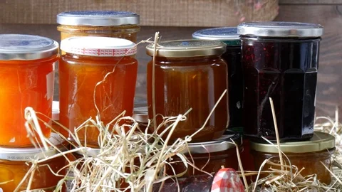 Moving camera slider showing  jars with different kinds of jam on straw Stock Footage 115702358