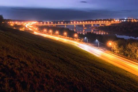Moving car with blur light through city at night. Bridge over the river and.. Stock Photos
