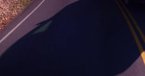 Moving car shadow on empty winding road Stock Footage 136341053