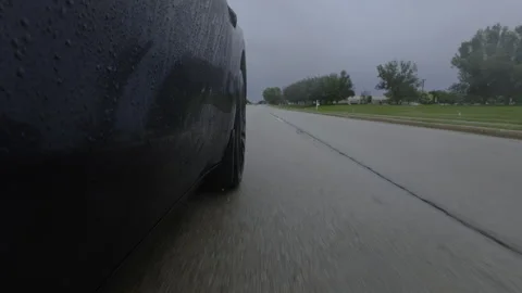 Moving car tire splashing through deep water during rain. Dramatic view of Vidéo 345475475