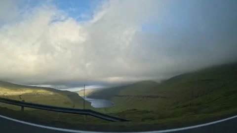 Moving car window view of green mountains under dramatic cloudy sky Stock Footage 339096815