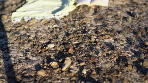 A moving close up on a shawl, straw hat, open book, sandy beach with blue waves. Stock Footage 134655313