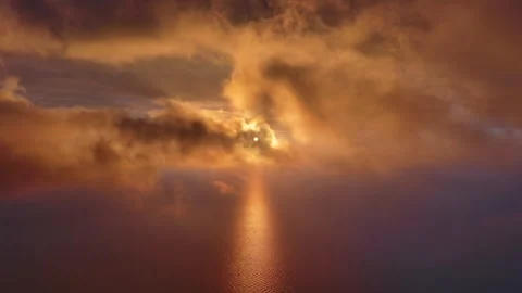 Moving in clouds to bright sun setting over calm sea Stock Footage 345448631