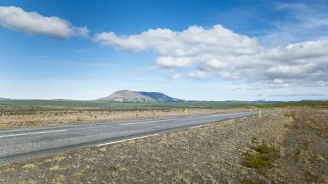 Moving clouds over a road crossing a vast rolling landscape in Iceland Video stock 136978124