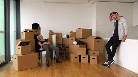 A moving couple talks seriously in a new apartment - piles of cardboard boxes in Stock-Footage 114875702