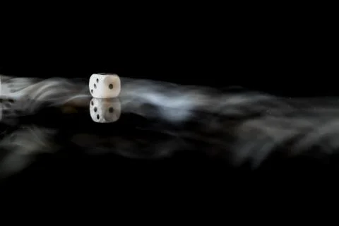 Moving die on a reflective surface with black background Foto stock