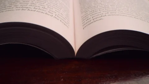 Moving fast over the middle of an open book at a low angle 8K Stock Footage 122604093