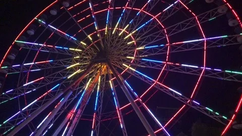 A moving ferris wheel glows in different colors at night. Stock-Footage 129521704