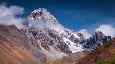 Moving fluffy clouds around Ushba peak in autumn sunny morning Stock Footage 58587290