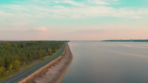 Moving forward behind a car along the water near the forest at sunset Stock Footage 127117325