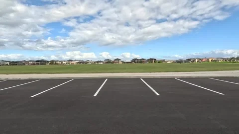 Moving forward from a public car park to a large grass,some houses in distance Vídeos de archivo 273568172