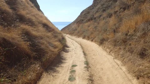 Moving forward on the road between clay mountains covered with dry grass. Stock Footage 156712579