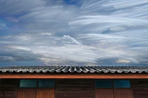 Moving of freezing cloud in blue sky over roof of wooden house Stock Photos