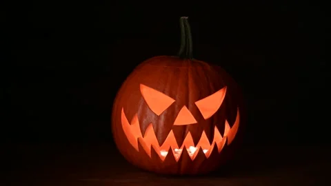 Moving glowing jack-o-lantern lit from inside on wooden table Stock Footage 317692790