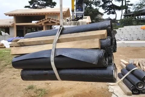 Moving to a height using a rope and lift, a roll of waterproofing roofing r.. Stock Photos