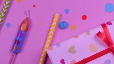 Moving holiday items of candles, gift boxes and confetti on pink background Stock Footage 245509734