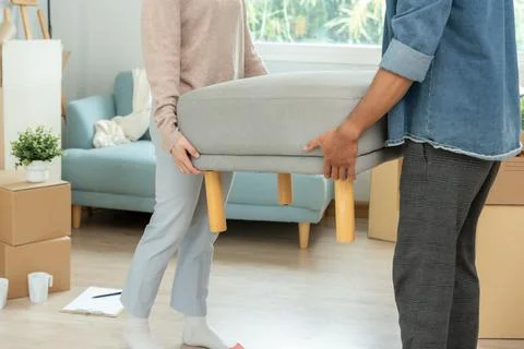 Moving house, relocation. Couple help set sofa and move furniture for new a.. Foto stock