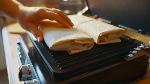 Moving lavash with stuffing on an electric grill by a hand for further cooking Stock Footage 237538600