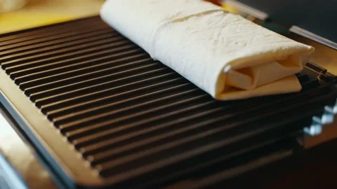 Moving lavash with stuffing on an electric grill by a hand for further cooking Stock Footage 238951862
