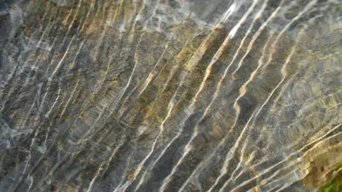 Moving lines of sunlight effects in water flowing over a rock Stock Footage 212737247