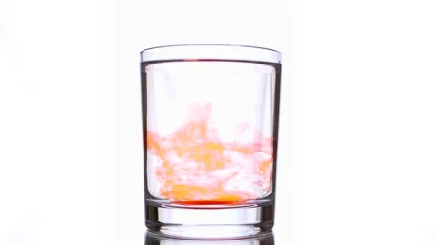 Moving of liquid orange paint falling into glass of water on white background Stock Footage 159483669