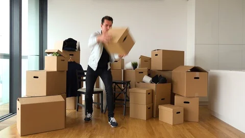 A moving man catches cardboard boxes thrown by someone off the camera and puts Stock Footage 114869970